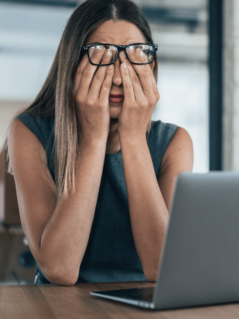 Frau mit Brille verdeckt Gesicht vor Laptop