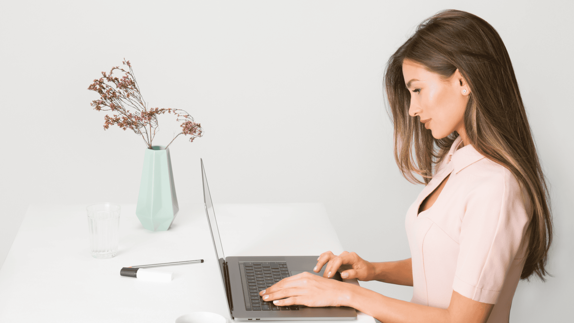 Frau arbeitet am Laptop an weißem Schreibtisch